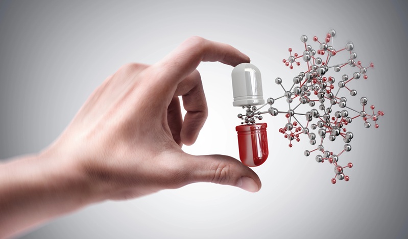 Hand holding pill with molecule
