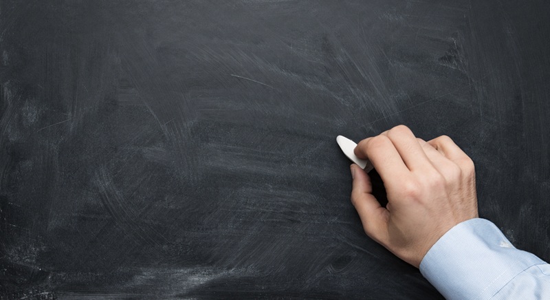 Blackboard with hand holding chalk, ready to write