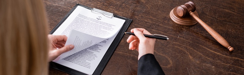  Image of a woman reviewing documents on a table with a gavel resting next to her on the table