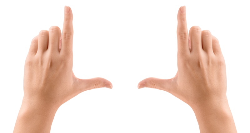 Image of two hands, thumbs and forefingers framing an unseen object in the distance