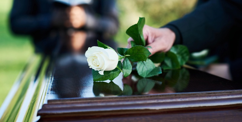 Family Member laying a flower on a coffin