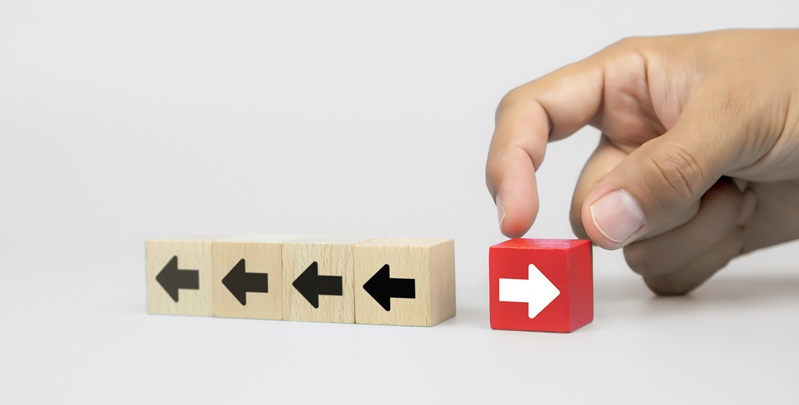 Image of blocks with arrows on them all pointing to the left, and a hand placing a block on the right, with an arrow pointing to the right
